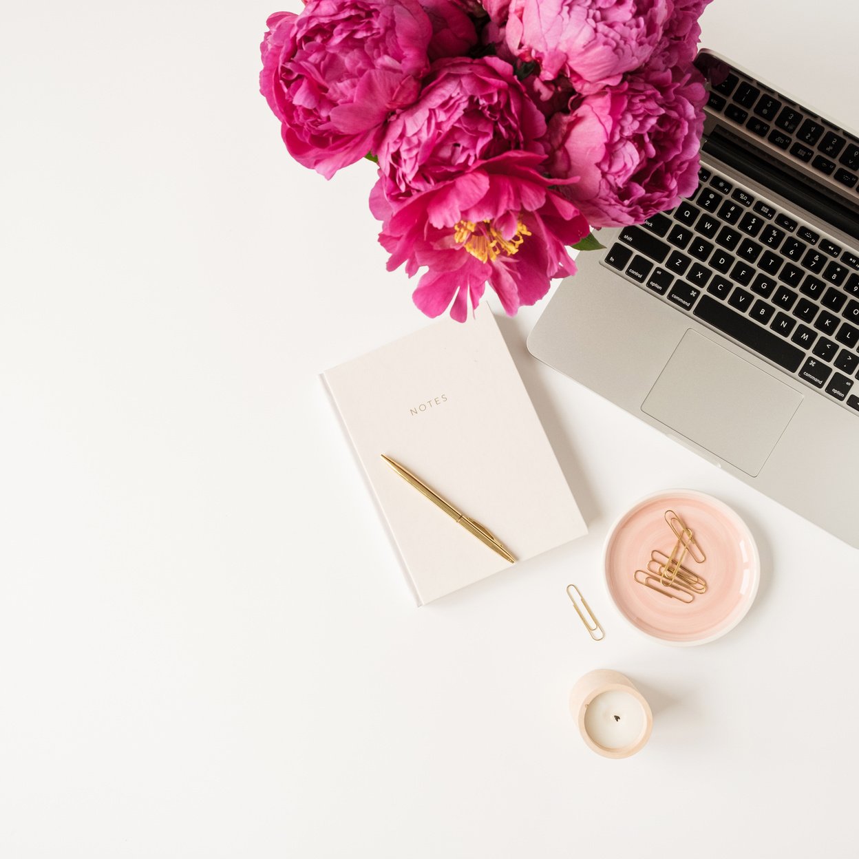 Laptop, Pink Peony Flowers, and Notebook on White Table.